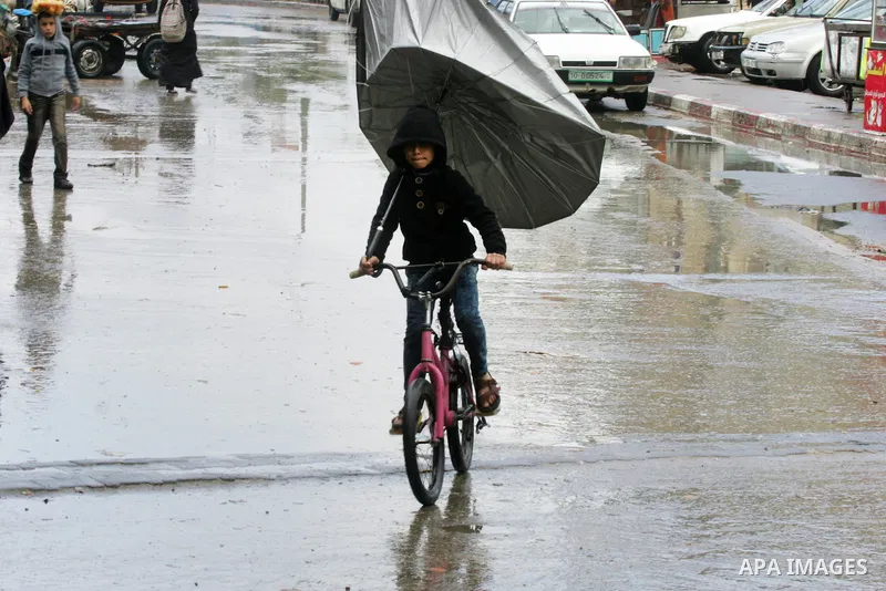 Palestinians walk in a flooded street during a rainy day, in Rafah in the southern Gaza strip on March 28, 2016. Photo by Abed Rahim Khatib