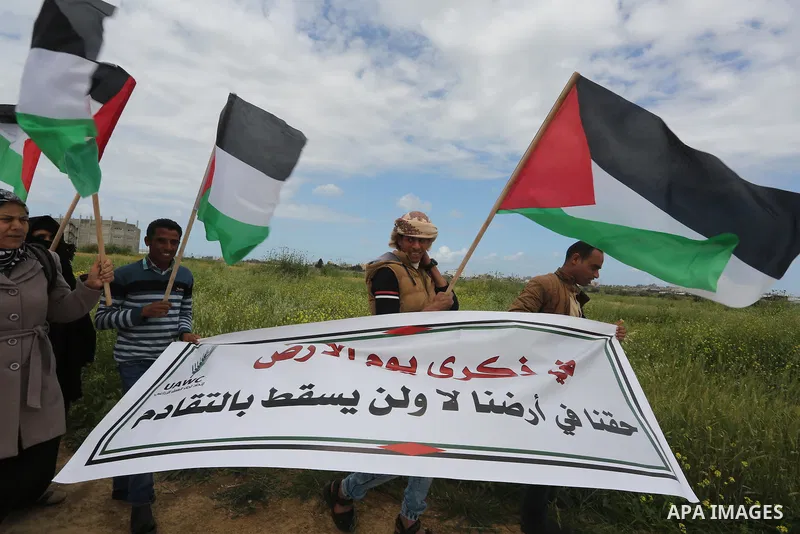 Palestinians hold national flags during a march to mark Land Day in Gaza, on March 29, 2016. The annual demonstrations mark the deaths of six Arab Israeli protesters at the hands of Israeli police and troops during mass...