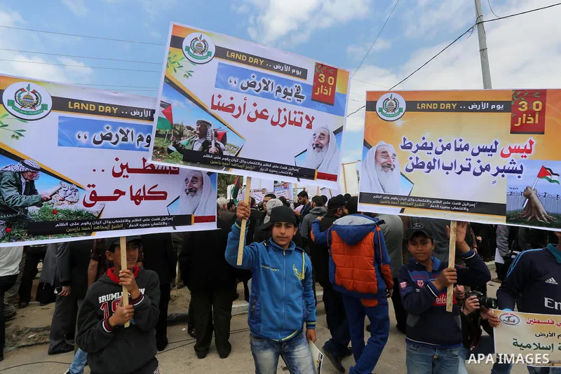 Palestinians hold banners and Palestine flags during a rally marking Land Day, near the Israeli border with northern Gaza Strip March 30, 2016. March 30 marks Land Day, the annual commemorations of the killing by police...