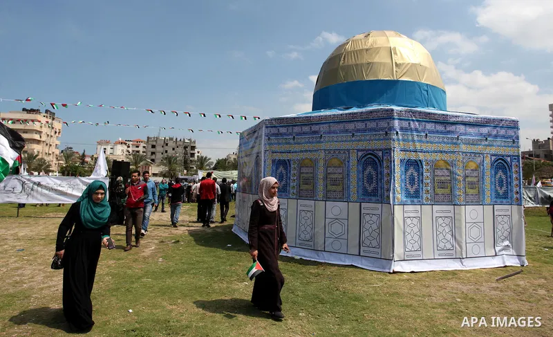 Palestinians walk past a model depicting the Dome of the Rock during a rally marking Land Day, in Gaza City March 30, 2016. March 30 marks Land Day, the annual commemorations of the killing by police of six Arab citizens...
