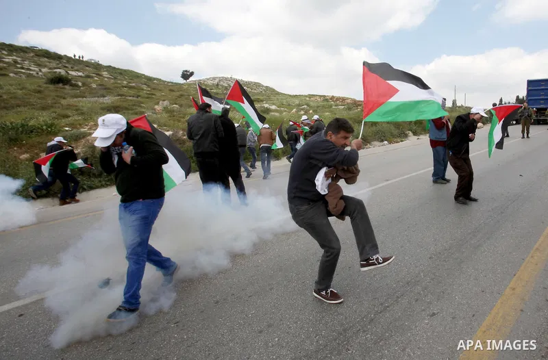 Palestinian demonstrators run for cover from tear gas fired by Israeli security forces during clashes following a rally marking Land Day in the West Bank village of Burqa near Nablus on March 30, 2016. March 30 marks Lan...