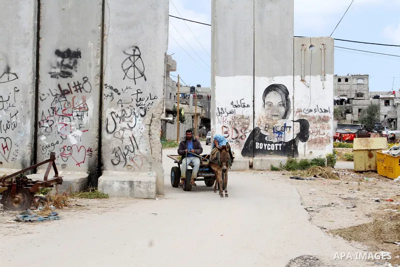 A Palestinian rides a donkey-drawn cart past a mural on March 30, 2016, in Khan Yunis, in the southern Gaza Strip as Palestinians mark Land Day. March 30 marks Land Day, the annual commemorations of the killing by police...