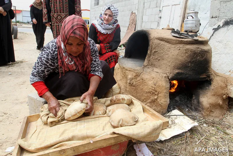 Palestinian women bake bread on March 30, 2016, in Khan Yunis, in the southern Gaza Strip as Palestinians mark Land Day. March 30 marks Land Day, the annual commemorations of the killing by police of six Arab citizens in...