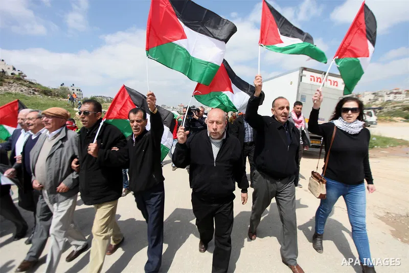 Palestinian protesters hold their national flag during a demonstration to mark Land Day outside the compound of the Israeli-run Ofer prison near Betunia in the Israeli occupied West Bank on March 30, 2016. March 30 marks...