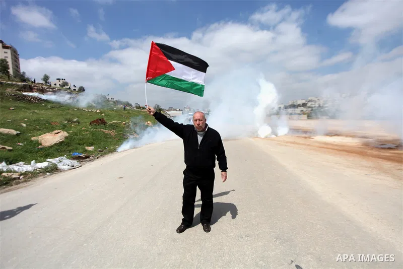 A Palestinian protester waves his national flag in front of Israeli security forces as they mark Land Day outside the compound of the Israeli-run Ofer prison near Betunia in the Israeli occupied West Bank on March 30, 20...