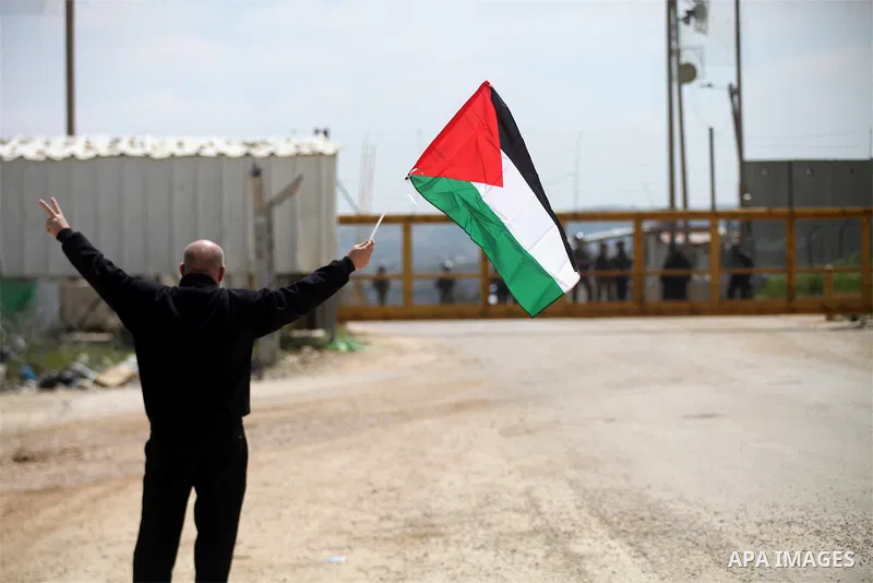 A Palestinian protester waves his national flag in front of Israeli security forces as they mark Land Day outside the compound of the Israeli-run Ofer prison near Betunia in the Israeli occupied West Bank on March 30, 20...