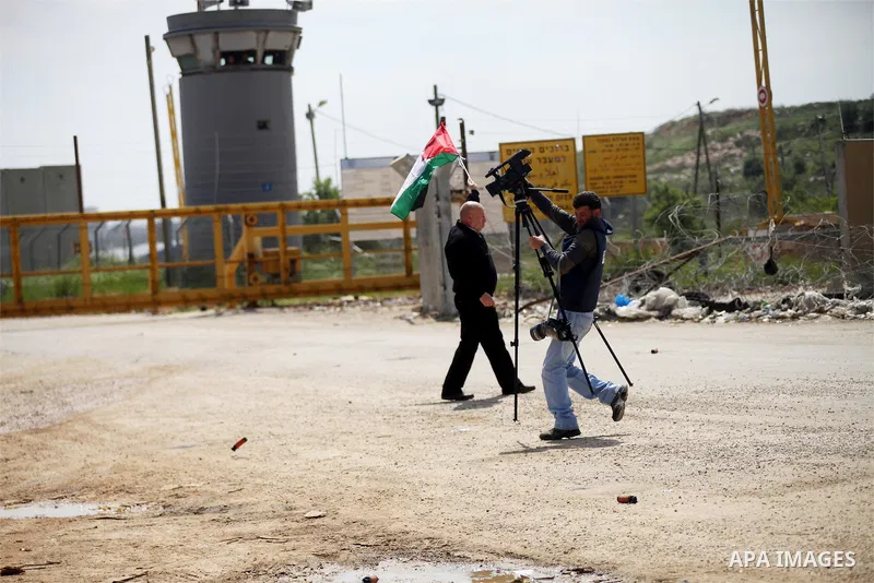 A Palestinian journalist runs for cover from tear gas fired by Israeli security forces during a demonstration to mark Land Day outside the compound of the Israeli-run Ofer prison near Betunia in the Israeli occupied West...