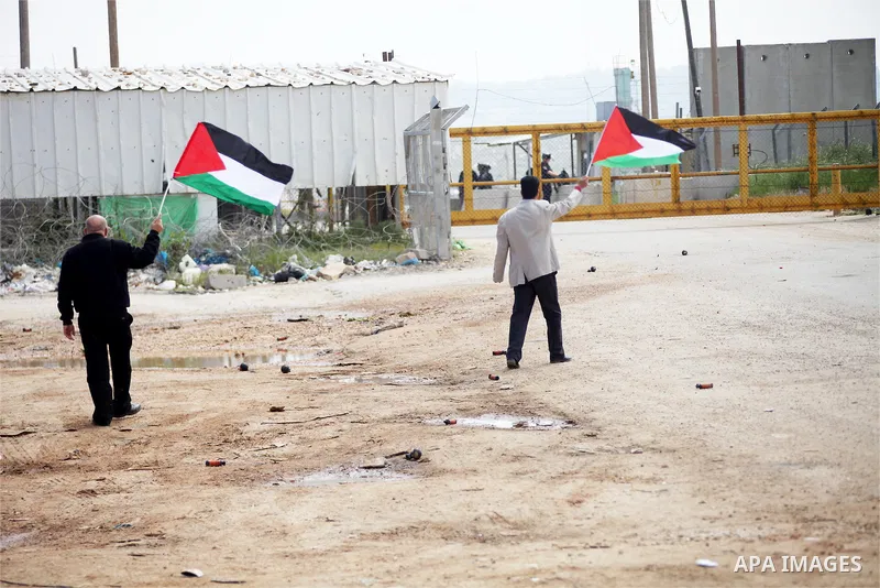 Palestinian protesters wave their national flag in front of Israeli security forces as they mark Land Day outside the compound of the Israeli-run Ofer prison near Betunia in the Israeli occupied West Bank on March 30, 20...
