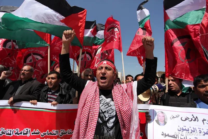 Palestinian protesters wave their national flags during a rally to mark Land Day, near the Nahal Oz crossing east of Gaza City on March 31, 2016. The annual commemorations of the killing by police of six Arab citizens in...