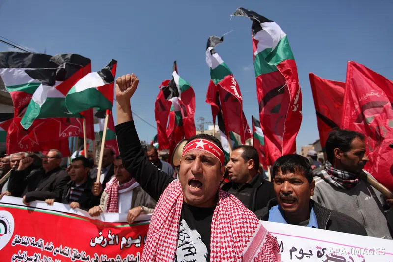 Palestinian protesters wave their national flags during a rally to mark Land Day, near the Nahal Oz crossing east of Gaza City on March 31, 2016. The annual commemorations of the killing by police of six Arab citizens in...