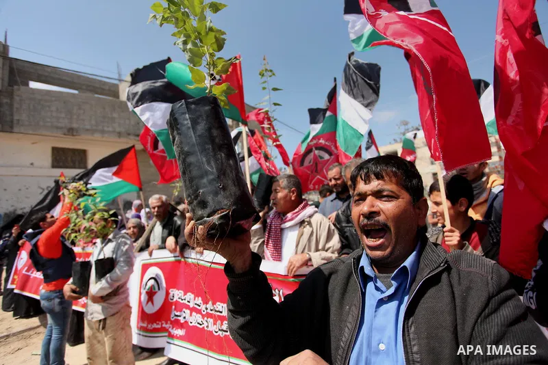 Palestinian protesters wave their national flags during a rally to mark Land Day, near the Nahal Oz crossing east of Gaza City on March 31, 2016. The annual commemorations of the killing by police of six Arab citizens in...
