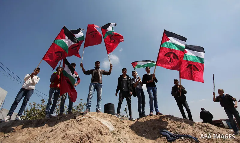 Palestinian protesters wave their national flags during a rally to mark Land Day, near the Nahal Oz crossing east of Gaza City on March 31, 2016. The annual commemorations of the killing by police of six Arab citizens in...