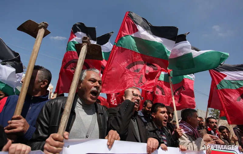 Palestinian protesters wave their national flags during a rally to mark Land Day, near the Nahal Oz crossing east of Gaza City on March 31, 2016. The annual commemorations of the killing by police of six Arab citizens in...