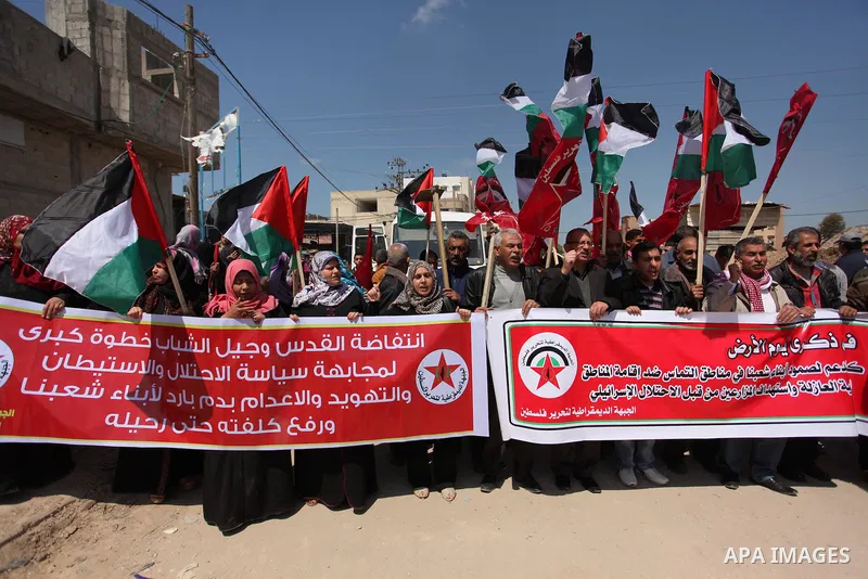 Palestinian protesters wave their national flags during a rally to mark Land Day, near the Nahal Oz crossing east of Gaza City on March 31, 2016. The annual commemorations of the killing by police of six Arab citizens in...