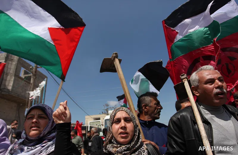 Palestinian protesters wave their national flags during a rally to mark Land Day, near the Nahal Oz crossing east of Gaza City on March 31, 2016. The annual commemorations of the killing by police of six Arab citizens in...