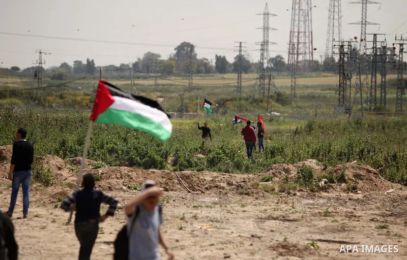 Palestinian protesters wave their national flags during a rally to mark Land Day, near the Nahal Oz crossing east of Gaza City on March 31, 2016. The annual commemorations of the killing by police of six Arab citizens in...