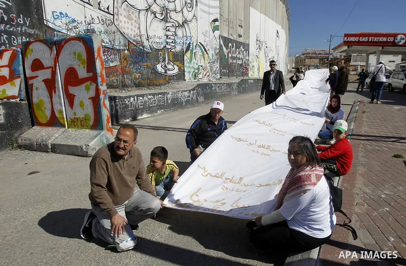 Participants run past the controversial Israeli barrier during the annual Right to Movement Palestine Marathon in the West Bank town of Bethlehem April 1, 2016. Photo by Wisam Hashlamoun