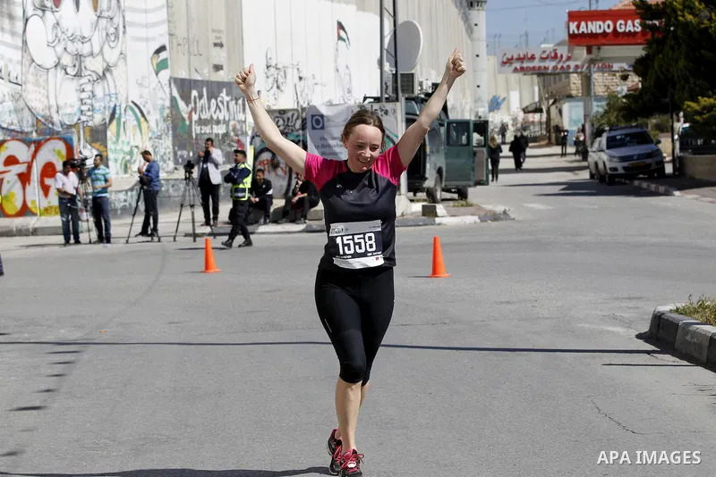 A participant runs near the controversial Israeli barrier during the annual Right to Movement Palestine Marathon in the West Bank town of Bethlehem April 1, 2016. Photo by Wisam Hashlamoun