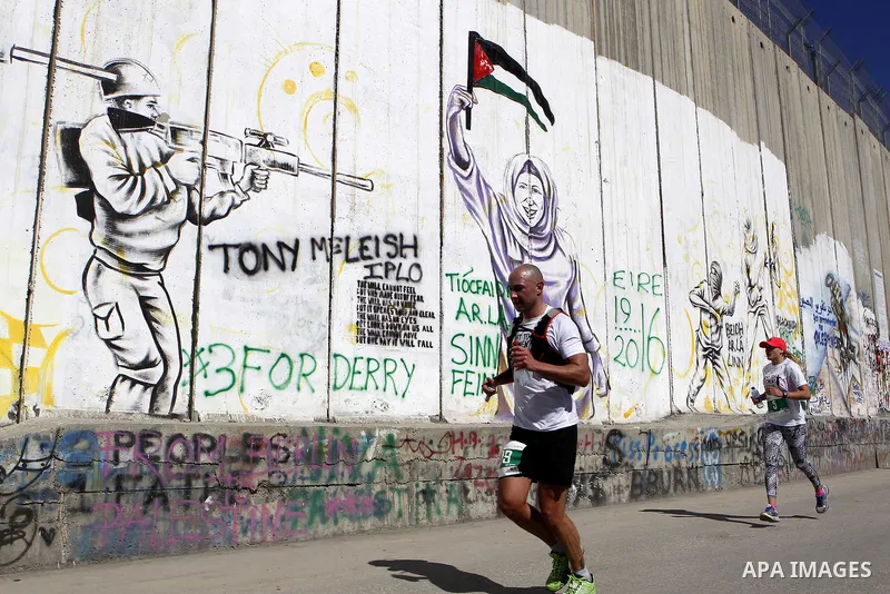 Participants run past the controversial Israeli barrier during the annual Right to Movement Palestine Marathon in the West Bank town of Bethlehem April 1, 2016. Photo by Wisam Hashlamoun