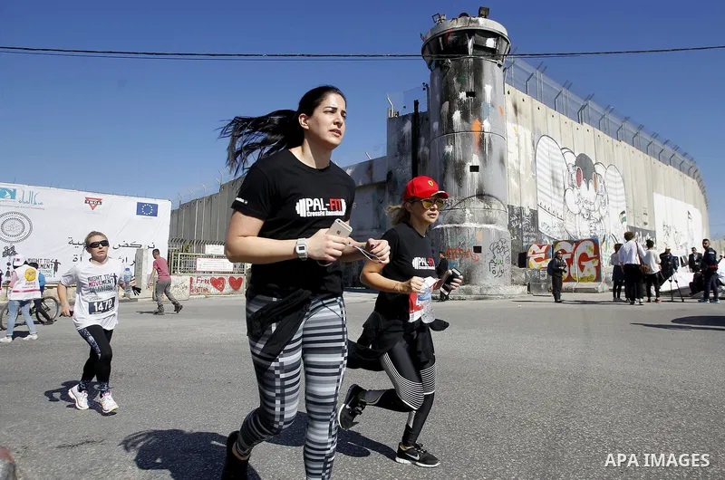 Participants run past the controversial Israeli barrier during the annual Right to Movement Palestine Marathon in the West Bank town of Bethlehem April 1, 2016. Photo by Wisam Hashlamoun