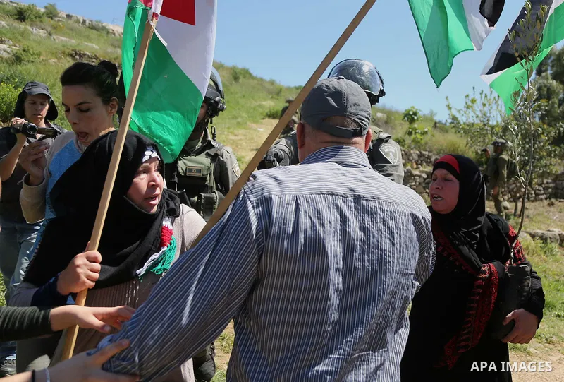 Palestinain protesters wave a national flag during clashes with Israeli border guards following a march against Palestinian land confiscation on April 1, 2016 in the West Bank village of Nabi Saleh near Ramallah. Photo b...