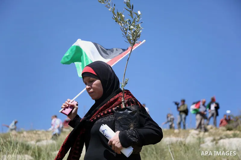 A Palestinain woman holds a national flag during clashes with Israeli border guards following a march against Palestinian land confiscation on April 1, 2016 in the West Bank village of Nabi Saleh near Ramallah. Photo by...