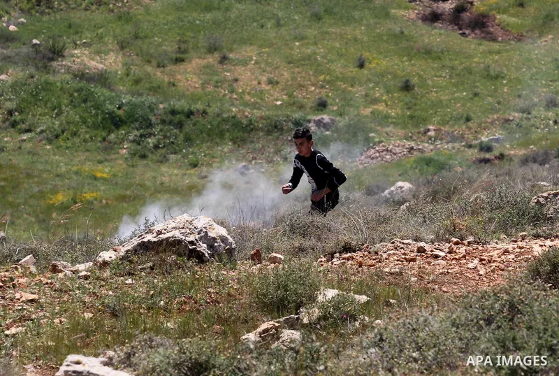 Palestinian protesters run for cover from tear gas fired by Israeli security forces during clashes following a demonstration against Jewish settlements in the West Bank village of Qaryout near Nablus on April 01, 2016. P...