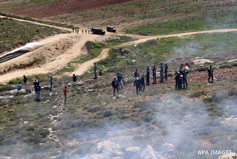 Palestinian protesters run for cover from tear gas fired by Israeli security forces during clashes following a demonstration against Jewish settlements in the West Bank village of Qaryout near Nablus on April 01, 2016. P...
