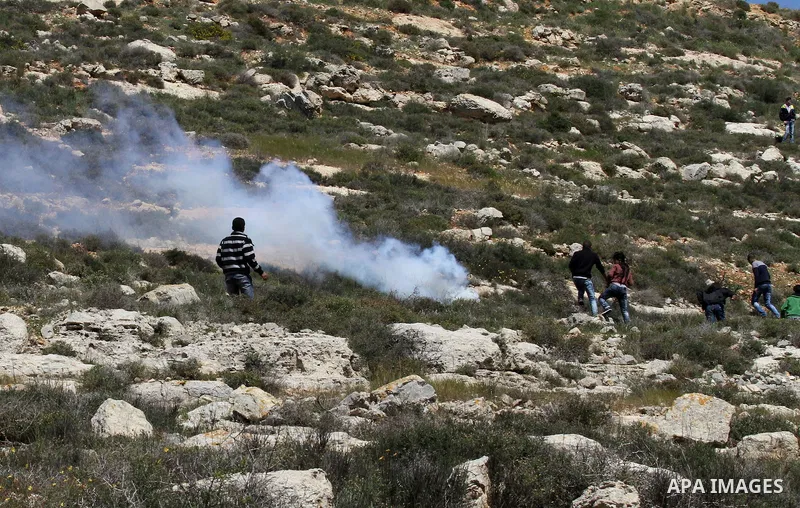 Palestinian protesters run for cover from tear gas fired by Israeli security forces during clashes following a demonstration against Jewish settlements in the West Bank village of Qaryout near Nablus on April 01, 2016. P...