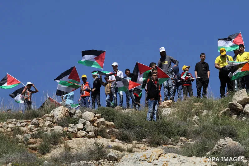 Palestinian protesters wave national flags during clashes with Israeli security forces following a demonstration against Jewish settlements in the West Bank village of Qaryout near Nablus on April 01, 2016. Photo by Neda...