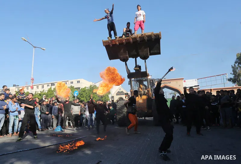 Participants ride in a bulldozer scoop as it is pulled by Palestinian Mohammad Baraka, nicknamed Gaza Samson, during a cultural carnival organized by Gaza Municipality in Gaza City April 1, 2016. Photo by Mohammed Asad
