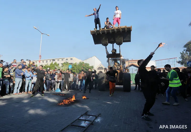 Participants ride in a bulldozer scoop as it is pulled by Palestinian Mohammad Baraka, nicknamed Gaza Samson, during a cultural carnival organized by Gaza Municipality in Gaza City April 1, 2016. Photo by Mohammed Asad