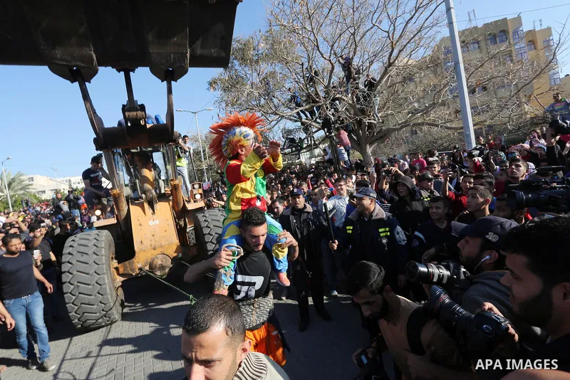 Palestinian Mohammad Baraka, nicknamed Gaza Samson, pulls a bulldozer by a rope tried around his waist as he holds a man dressed as a clown during a cultural carnival organized by Gaza Municipality in Gaza City April 1,...