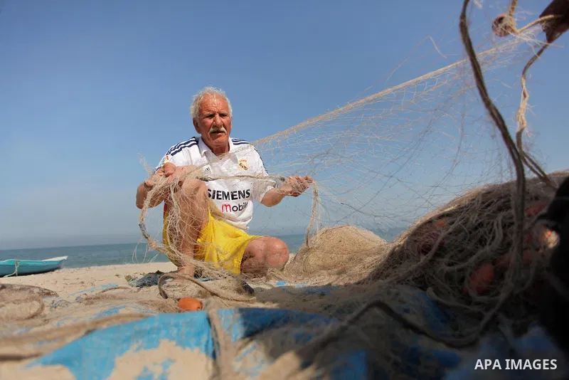Palestinian fishermen collect fish from their nets at the beach in Gaza City on April 03, 2016. Israel on Sunday extended the distance it permits Gaza fishermen to head out to sea along certain parts of the coastline of...