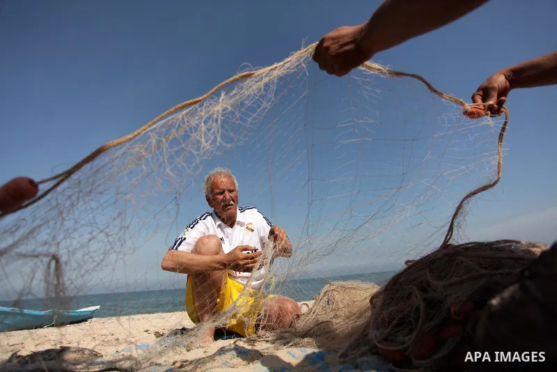 Palestinian fishermen collect fish from their nets at the beach in Gaza City on April 03, 2016. Israel on Sunday extended the distance it permits Gaza fishermen to head out to sea along certain parts of the coastline of...