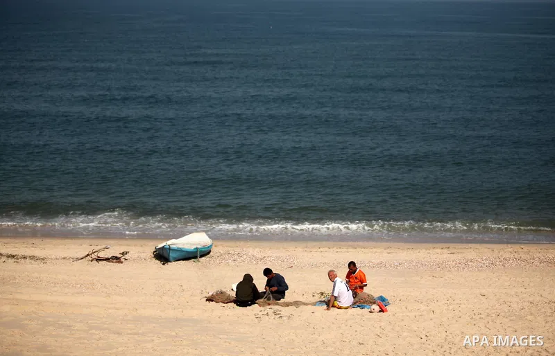 Palestinian fishermen work at the beach in Dair Al Balah in the center of Gaza strip on April 03, 2016. Israel on Sunday extended the distance it permits Gaza fishermen to head out to sea along certain parts of the coast...
