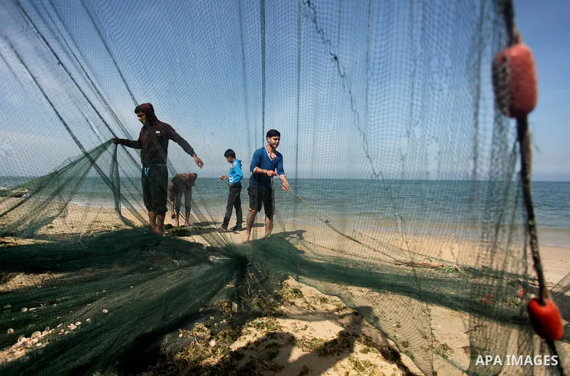 Palestinian fishermen pull their net at the beach in Gaza City on April 03, 2016. Israel on Sunday extended the distance it permits Gaza fishermen to head out to sea along certain parts of the coastline of the enclave, w...