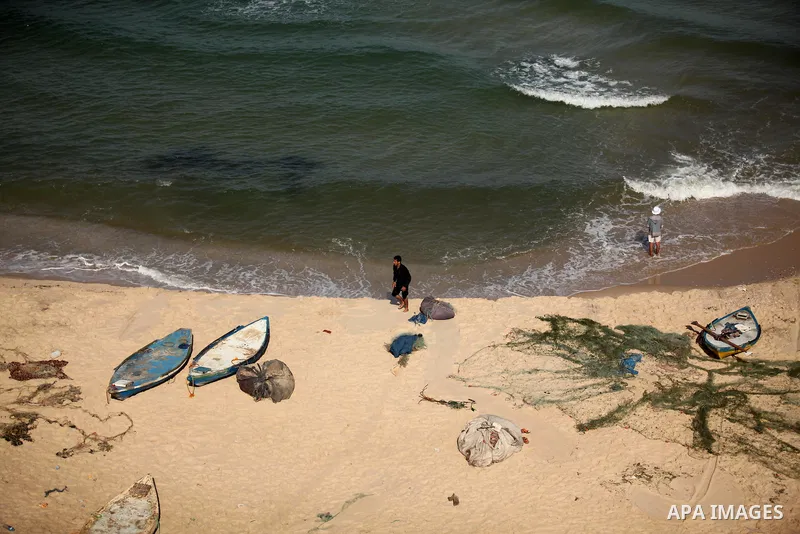 Palestinian fishermen work at the beach in Dair Al Balah in the center of Gaza strip on April 03, 2016. Israel on Sunday extended the distance it permits Gaza fishermen to head out to sea along certain parts of the coast...