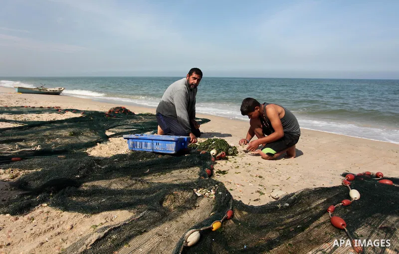 Palestinian fishermen collect fish from their nets at the beach in Gaza City on April 03, 2016. Israel on Sunday extended the distance it permits Gaza fishermen to head out to sea along certain parts of the coastline of...