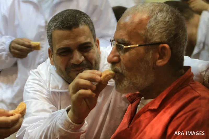 Egyptian Muslim Brotherhood leader Mohammed Badie eats sweets at the defendant's cage as he attends his trial, at a court in the outskirts of Cairo, Egypt, on April 03, 2016. Photo by Stranger