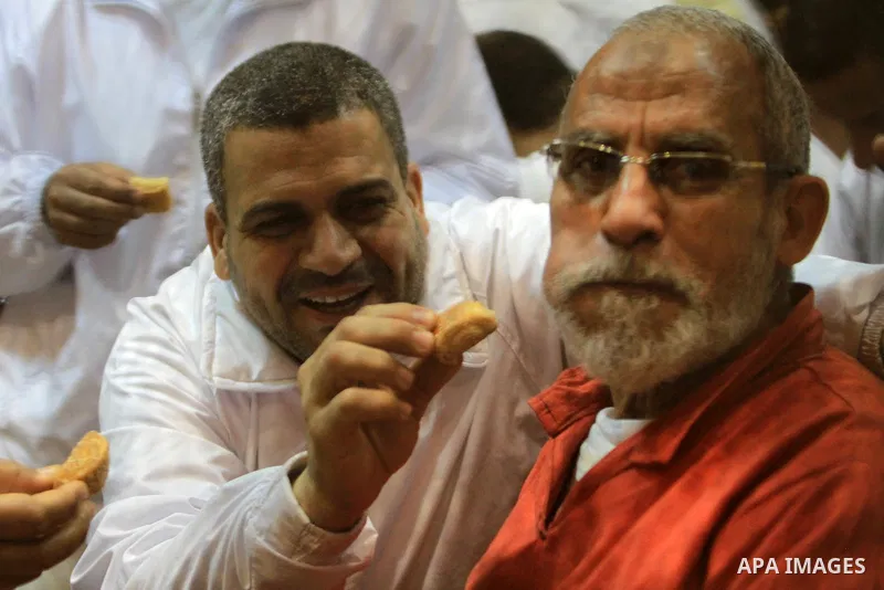 Egyptian Muslim Brotherhood leader Mohammed Badie eats sweets at the defendant's cage as he attends his trial, at a court in the outskirts of Cairo, Egypt, on April 03, 2016. Photo by Stranger