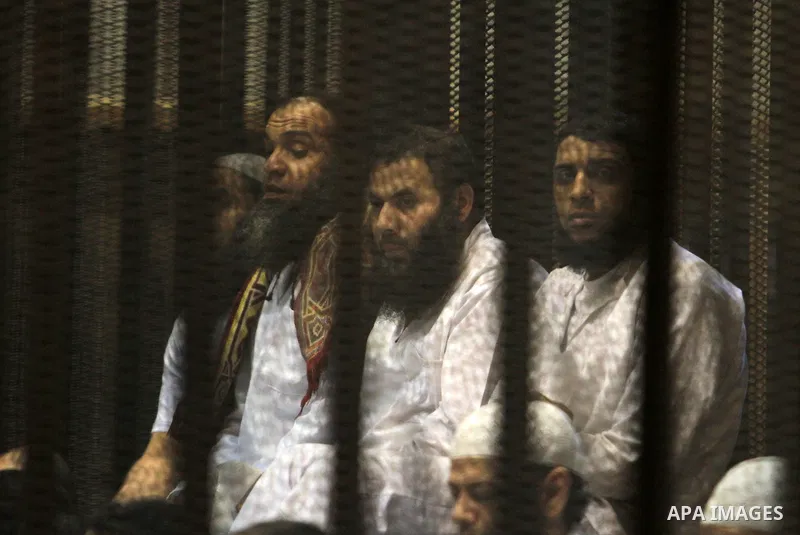 Muslim Brotherhood members sit behind the defendants cage as they attend their trial along with Egyptian Muslim Brotherhood leader Mohammed Badie (unseen), at a court in the outskirts of Cairo, Egypt, on April 03, 2016....