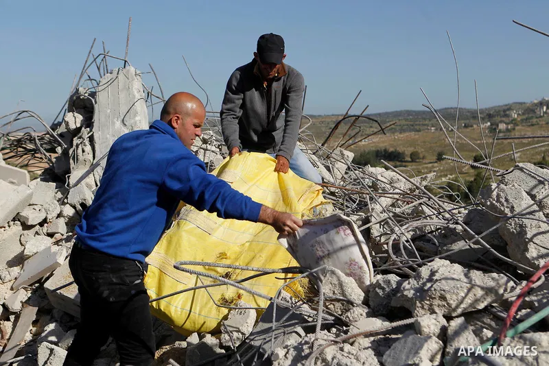 Palestinians collect belongings near the rubble of their house that were demolished by the Israeli army, after Israeli authorities said it was built without a permit, in the village of Sourif the west bank city of Hebron...