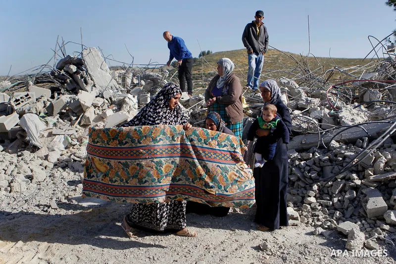 Palestinians collect belongings near the rubble of their house that were demolished by the Israeli army, after Israeli authorities said it was built without a permit, in the village of Sourif the west bank city of Hebron...
