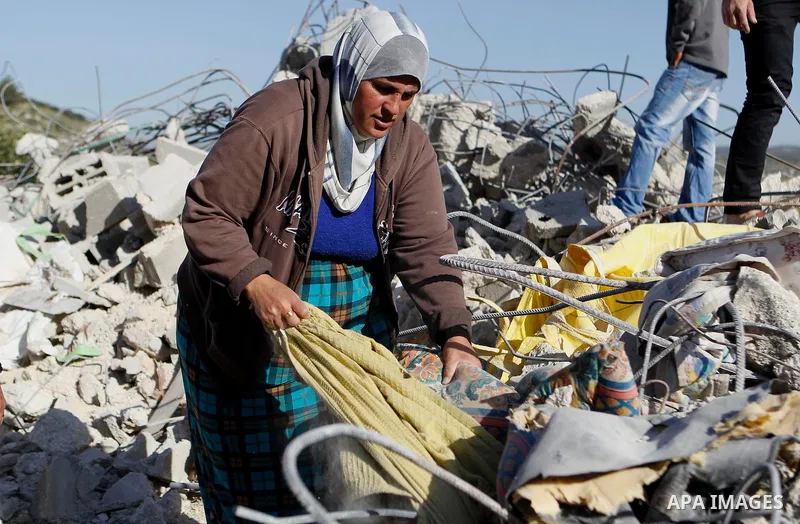 Palestinians collect belongings near the rubble of their house that were demolished by the Israeli army, after Israeli authorities said it was built without a permit, in the village of Sourif the west bank city of Hebron...