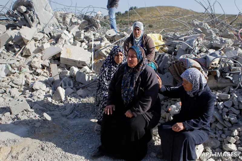 Palestinians collect belongings near the rubble of their house that were demolished by the Israeli army, after Israeli authorities said it was built without a permit, in the village of Sourif the west bank city of Hebron...