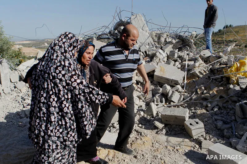 Palestinians collect belongings near the rubble of their house that were demolished by the Israeli army, after Israeli authorities said it was built without a permit, in the village of Sourif the west bank city of Hebron...