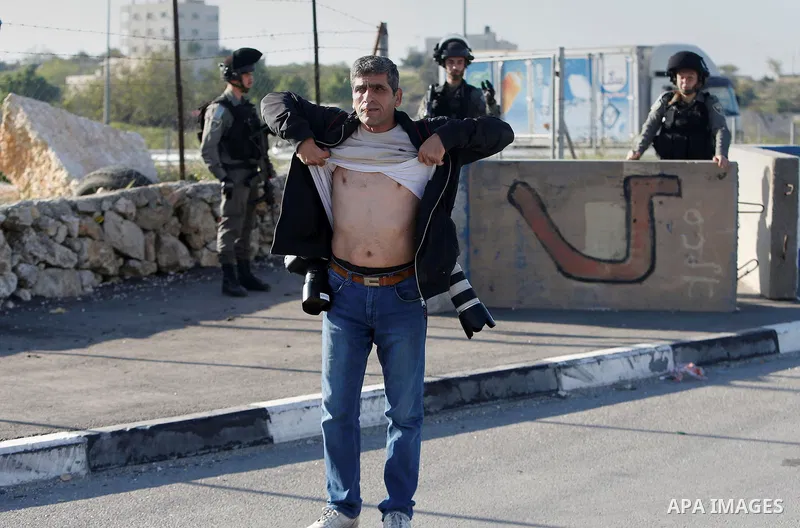 Israeli border policemen check a Palestinian Photographer at the Beit Ainun junction near the West Bank city of Hebron, on April 4, 2016. The man reportedly was arrested within the usual security measures taken in the re...