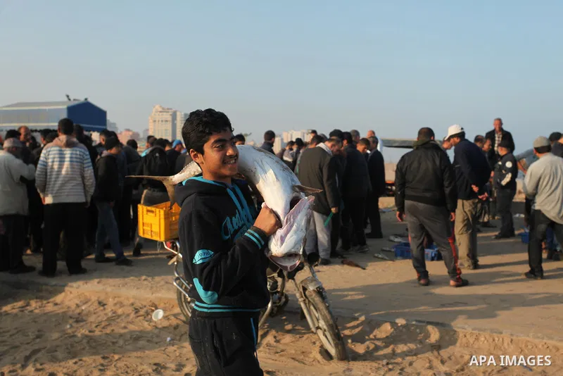 A Palestinian boy displays fish for sale, in Gaza seaport, on April 4, 2016. Israel on Sunday extended the distance it permits Gaza fishermen to head out to sea along certain parts of the coastline of the enclave, which...