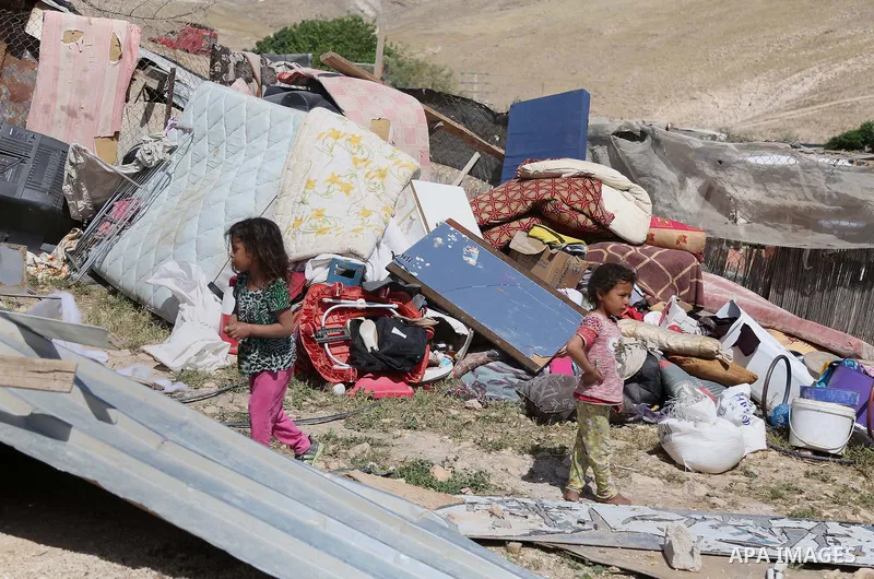 children from the Arab Jahalin Bedouin community play past the debris of homes in the West Bank Bedouin camp of al-Khan al-Ahmar on April 7, 2016 after Israeli authorities demolished four houses that they said were built...